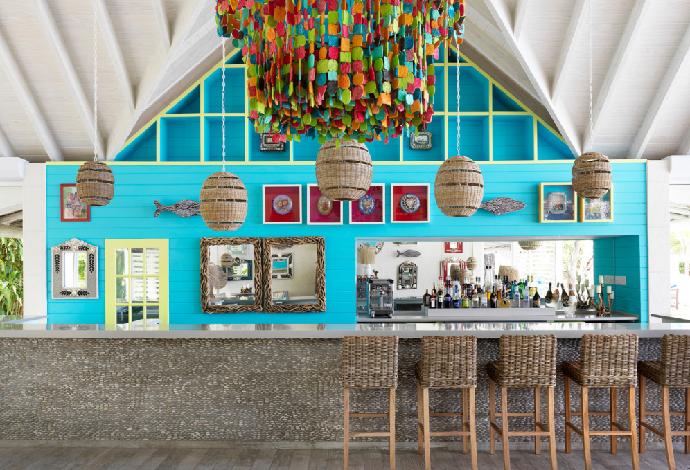 Wicker pendant lights hang above a colourful bar with wicker bar stools